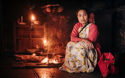 Depiction of a Khasi lady in a kitchen using just lamp lights and wood for cooking
